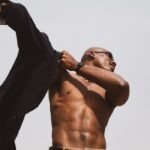 Athletic man with sunglasses posing outdoors, showcasing strength and style in Lagos.