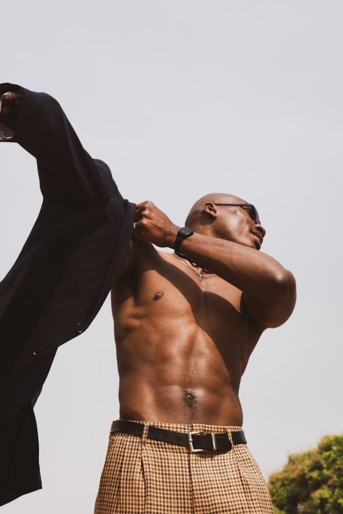 Fit, confident man putting on a black shirt outdoors, representing physical traits women find attractive in dating.