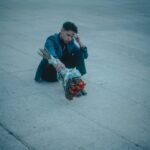 A young man holding roses sits pensively on a street in Mexico City.