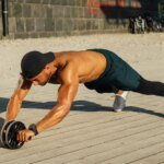 Fit man in outdoor workout using ab roller, showcasing strength and fitness.