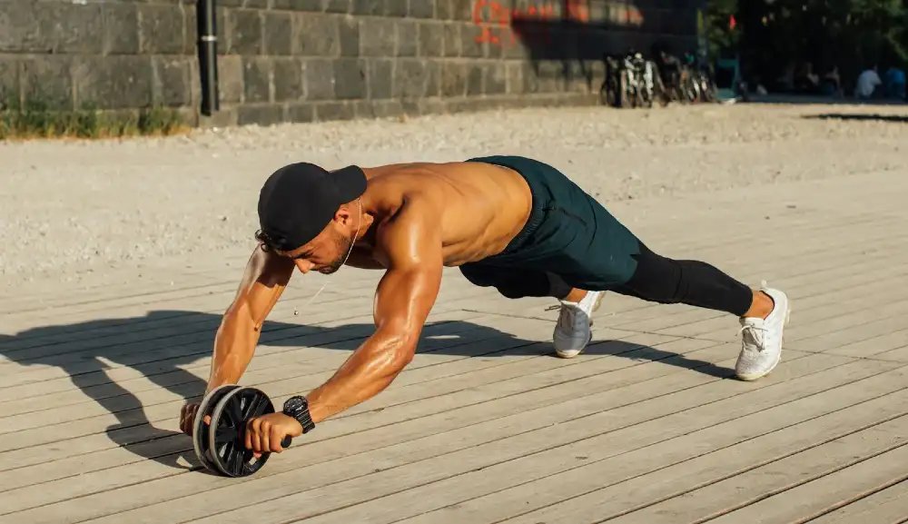 Fit man in outdoor workout using ab roller, showcasing strength and fitness.