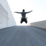 Man jumping on urban road with arms spread wide in Dubai, showcasing freedom and energy.