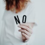 Close-up of a person holding a "No" sign, symbolizing rejection or disagreement.