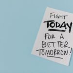 Inspirational handwritten message urging action for a better future on paper over a blue backdrop.