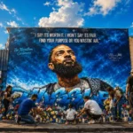 Fans leave flowers and candles at a Nipsey Hussle mural tribute, honoring his legacy of ownership and community impact